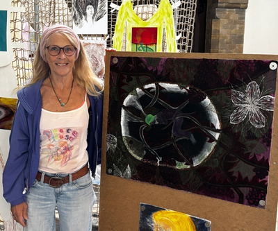 Zu sehen ist die Künstlerin Barbara Tamminga vor dem Bild mit dem Titel „Brombeerkind“.