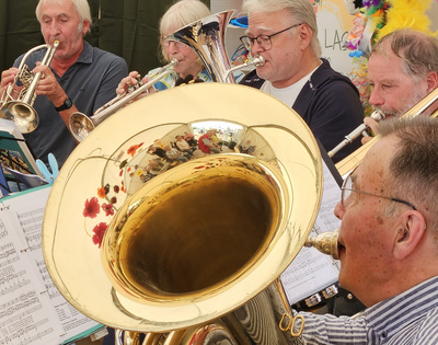 In der Spiegelung der Tuba sieht man das Kirchenzelt, im Hintergrund sitzen weitere Bläser.