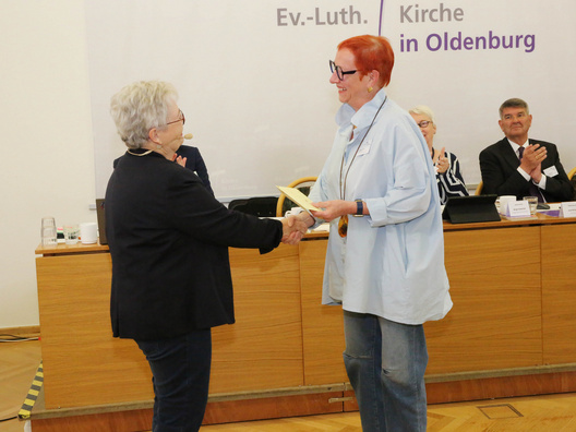 Auf dem Bild sind die Synodenpräsidentin Sabine Blütchen (links) bei der Ehrung der Synodalen Susanne Bruns für 20 Jahre Mitgliedschaft in der Synode zu sehen.