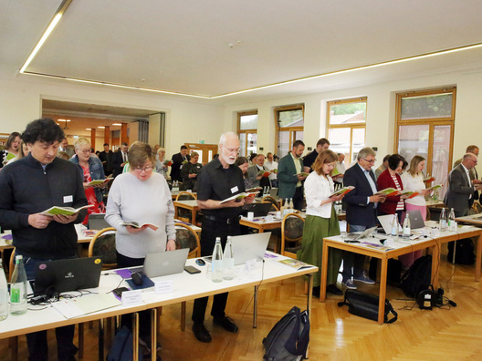 Viele Menschen stehen und singen in einem Raum.