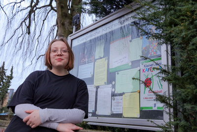 Julia Berse steht vor dem Schaukasten der Kirchengemeinde Cloppenburg.