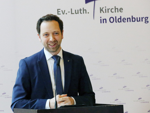 Oberkirchenrat Sebastian Groß steht am Rednerpult und spricht.