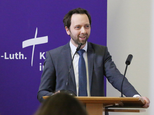 Oberkirchenrat Sebastian Groß steht am Rednerpult.