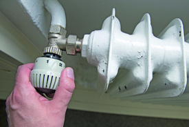 Thermostat an einer Heizung (Foto in CMYK) Eine Hand stellt die Temperatur an einer Heizung ein