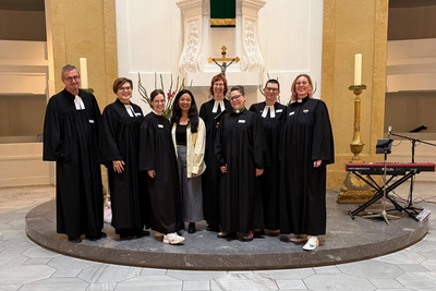 Zu sehen ist das Team von Taufe to go in der Oldenburger Lambertikirche (von links nach rechts): Kreispfarrer Torsten Maes, Pfarrerin Patrizia Mandel-Birajdar, Pfarrerin Anna Menke, Popkantorin Sarina Lal, Pfarrerin Gesa Schaer-Pinne, Pfarrerin Meike Melchinger, Pfarrerin Jennifer Battram-Arenhövel und Pfarrerin Nele Schomakers.