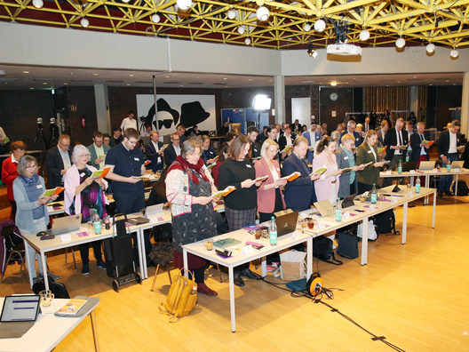 Menschen stehen und singen während einer Andacht.