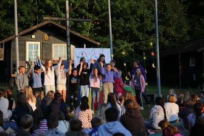 Kinder und Jugendliche sind draußen zu einem Abendgottesdienst versammelt