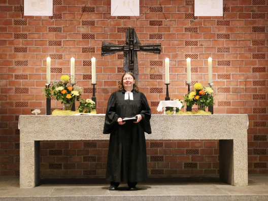 Eine Pfarrerin steht vor dem Altar in der Kirche und predigt.