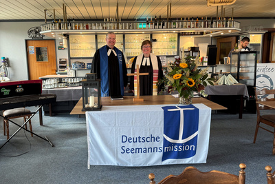 Zu sehen sind Pfarrerin Susanne Stephan (rechts) und Seemannspastor Dirk Jährig aus Brake (links) beim Seemannsgottesdienst im Restaurant Nordseeblick direkt am Hafen von Fedderwardersiel.