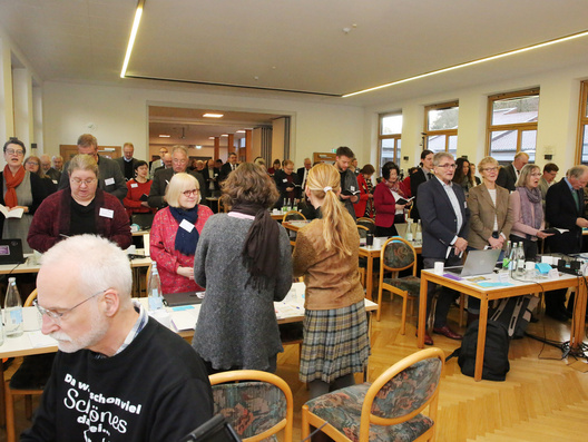 Viele Menschen stehen im Raum und singen.