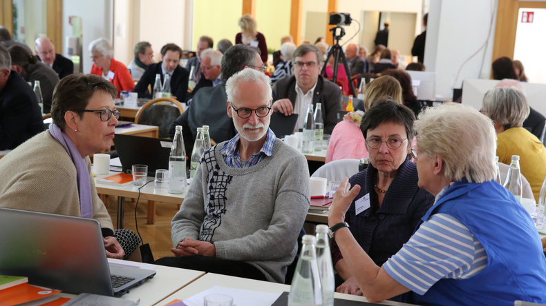 Synodale der oldenburgischen Kirche tauschen sich angeregt während einer Tagung aus.