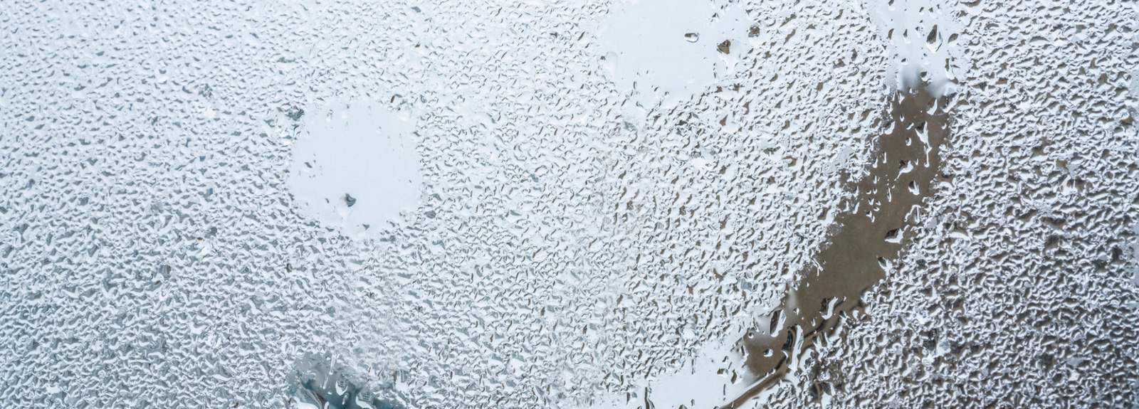 Auf einer regennassen Glasscheibe ist ein Smiley mit den Fingern gemalt worden. 