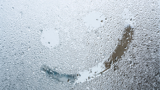 Auf einer regennassen Glasscheibe ist ein Smiley mit den Fingern gemalt worden. 