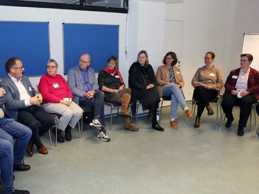 Viele Menschen sitzen in einem Raum und diskutieren.