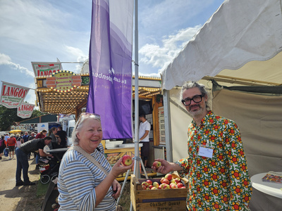 Esben Fest vom Messeteam steht vor dem Kirchenzelt und gibt einer Besucherin einen Apfel