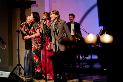 Fünf Personen stehen auf der Bühne, vier Frauen singen im Vordergrund.