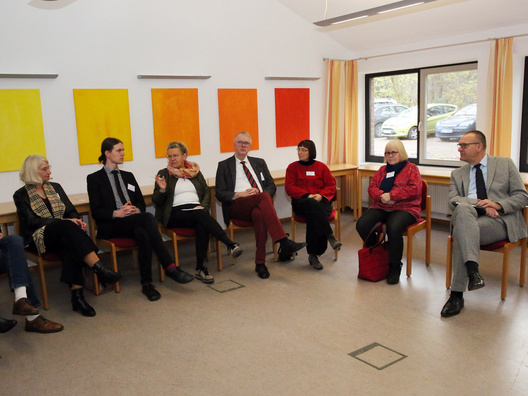 Viele Menschen sitzen in einem Raum und diskutieren.