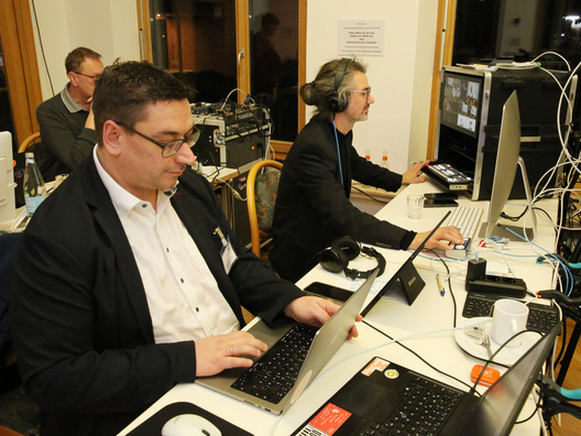 Zwei Männer sitzen an Computern und arbeiten.