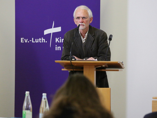 Der Synodale Carsten Homann steht am Rednerpult.