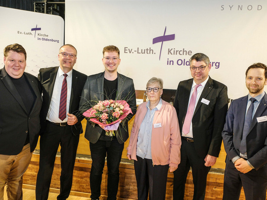 Mehrere Menschen stehen mit dem neuen Synodenpräsidenten vor der Kamera und gratulieren.