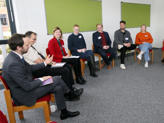Viele Menschen sitzen in einem Raum und diskutieren.