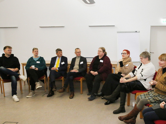 Viele Menschen sitzen in einem Raum und diskutieren.