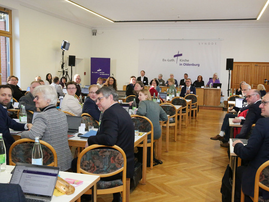 Viele Menschen, die Synode, sitzen in einem großen Raum.