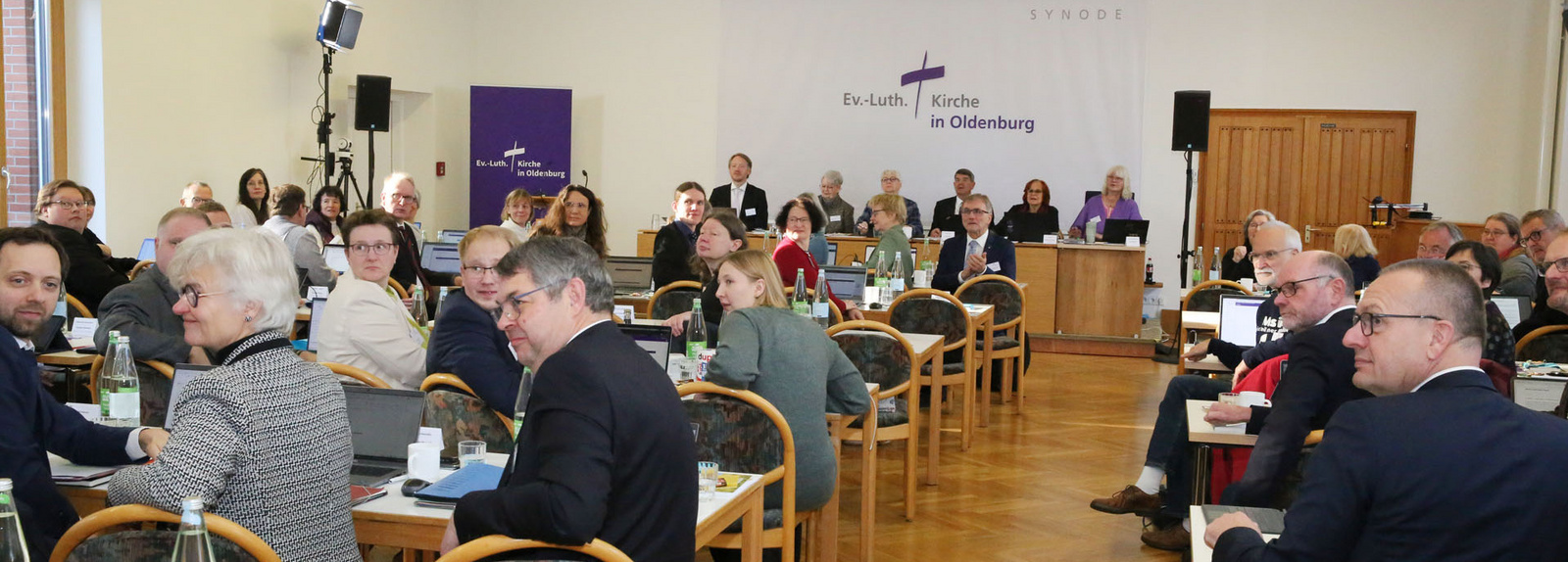 Viele Menschen, die Synode, sitzen in einem großen Raum.