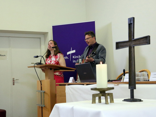 Am Rednerpult stehen die Synodale Sarah Kruse und Pfarrer Cornelius Gross.