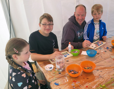 Zu sehen ist ein Vater, der mit seinen Kindern viel Freude am Basteln hat.