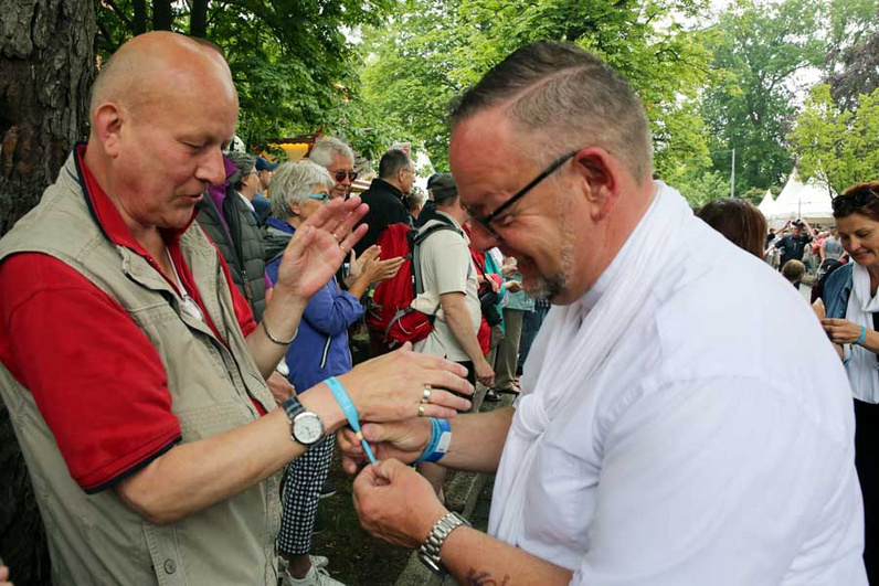Kreispfarrer Christian Scheuer verteilt beim Trachtenumzug Segenbänder an die Passanten. Foto: D.-M. Grötzsch
