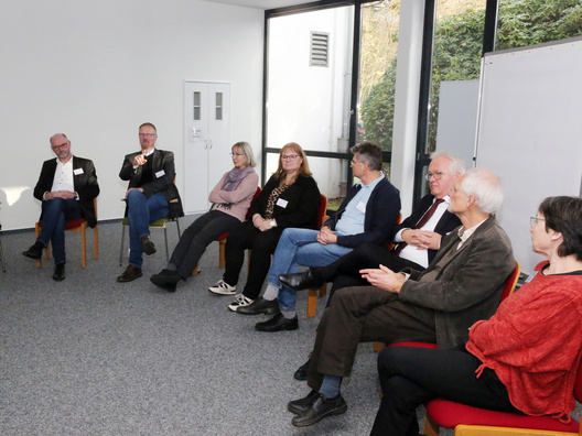 Viele Menschen sitzen in einem Raum und diskutieren.