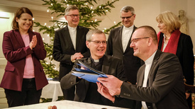 Vertragsunterzeichnung Bischof Dr. Heiner Wilmer, Bistum Hildesheim (links), und Bischof Thomas Adomeit, Ratsvorsitzender der Konföderation evangelischer Kirchen in Niedersachsen (rechts), tauschen die unterschriebene Vereinbarung zum neuen Unterrichtsfach Christliche Religion aus. Links daneben steht die niedersächsische Kultusministerin Julia Willie Hamburg.