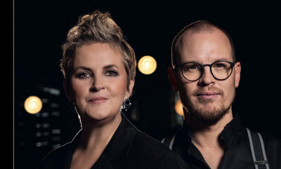 Ein Foto vom Duo Christina Brudereck und Ben Seipel vor schwarzem Hintergrund