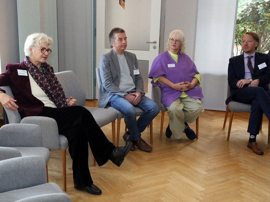 Viele Menschen sitzen in einem Raum und diskutieren.