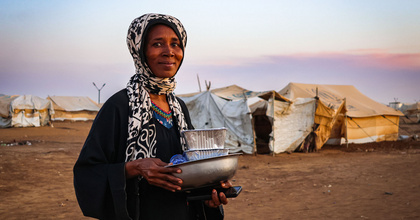Zu sehen ist eine Frau im Sudan mit Artikeln des täglichen Bedarfs in den Händen.