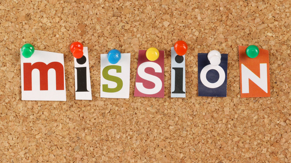An einer Kork Pinwand stehen verschiedene ausgeschnittene Buchstaben, die das Wort Mission ergeben.