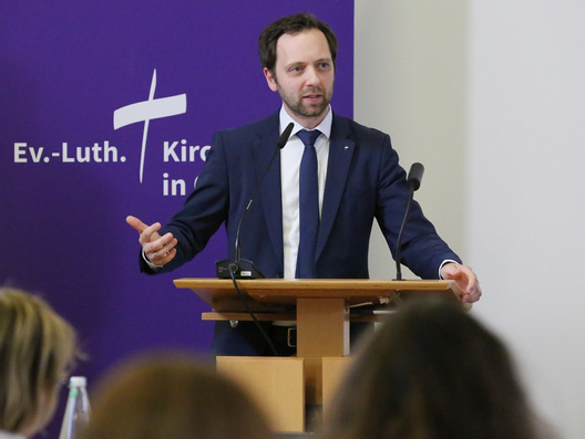 Oberkirchenrat Sebastian Groß steht am Rednerpult.