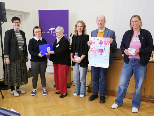 Auf diesem Foto ist zu sehen wie vertretend für queere Menschen in der oldenburgischen Kirche Pfarrerin Jennifer Battram-Arenhövel (sie/ihr), Tom Heymann (er/ihm), Kim König (sie/ihr), Sören Koselitz (er/ihm) und Pfarrerin Nele Schomakers (sie/ihr) Forderungen an Synododenpräsidentin Sabine Blütchen, die auf der Veranstaltungen "Queer gesprochen" gesammelt worden waren, übergeben wurden.